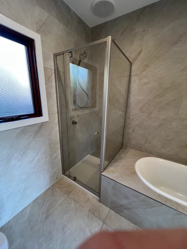 Semi-framed brushed nickel shower screen beside a bath